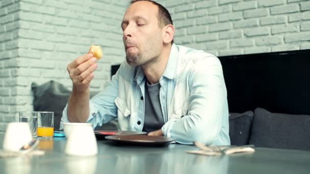 Hombre comiendo sabroso bollo dulce en la cafetería — Vídeos de Stock