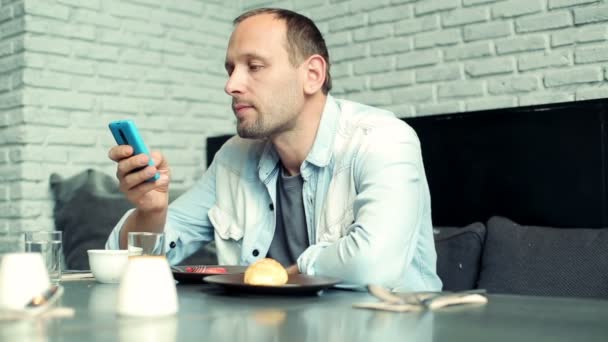 Mann schreibt SMS auf Smartphone und trinkt Saft — Stockvideo