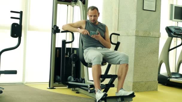 Hombre con Smartphone en el Gimnasio — Vídeos de Stock