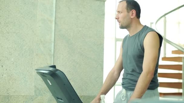 Man drinking water during walk on treadmill — Stock Video