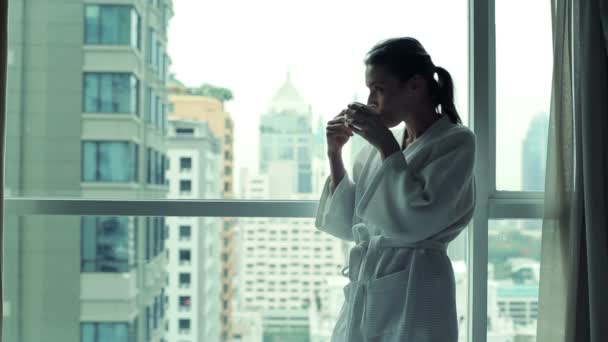 Frau trinkt Kaffee am Fenster — Stockvideo