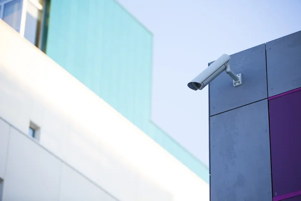 Camera system guarding blue skyscraper office building with blue sky above in horizontal format — Stock Photo, Image