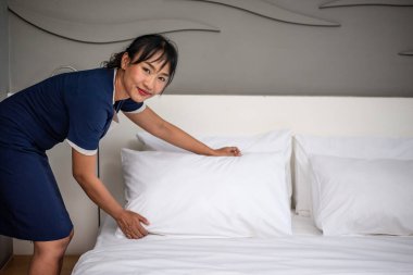 Otel hizmetçisi yatağı ve otel odasını temizliyor.