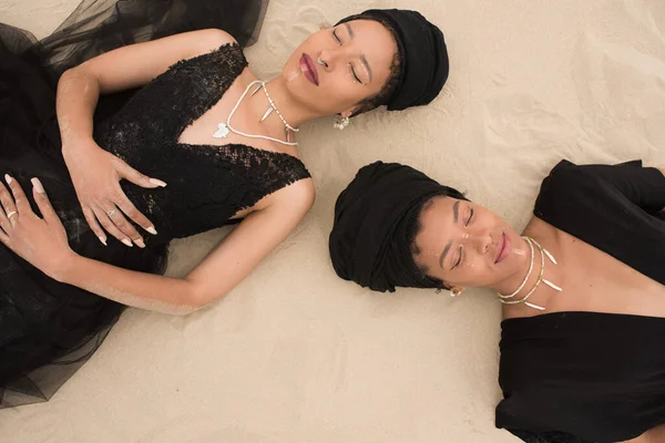 Porträt zweier Damen, die auf Sand liegen — Stockfoto