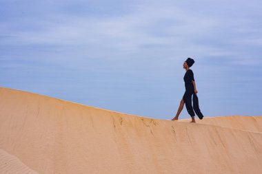 Kum tepeciği boyunca yürüyen bir kadın