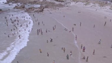 Drone flying over people seen on shoreline 