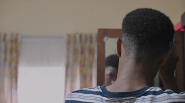 Afro tarak kullanan bir gencin arka görünüşü