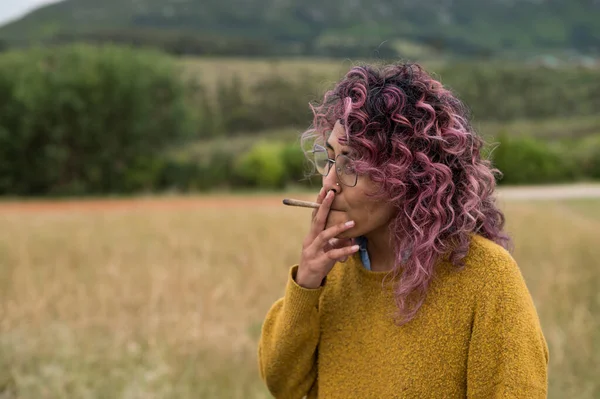 Retrato de una mujer de pie fumando un porro de cannabis — Foto de Stock
