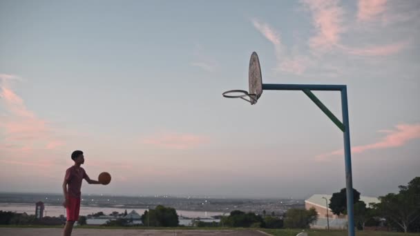 Мальчик играет в баскетбол один на площадке — стоковое видео
