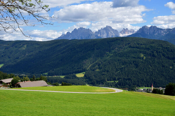 Beginning of the Val Casies, large pine forests and the green meadows of the village of Tesido with the backdrop of the Dolomites