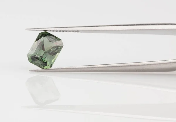 Green Sapphire Gemstone in Tweezers