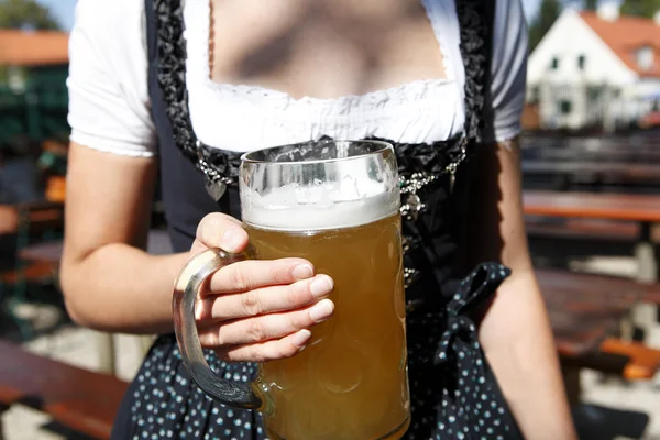 Jonge vrouw met een mok van bier in de biertuin — Stockfoto