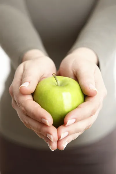 Female hands with a green apple — Stock Photo, Image