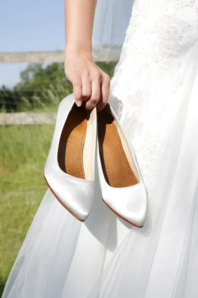Mariée tient des chaussures de mariée dans la main — Photo