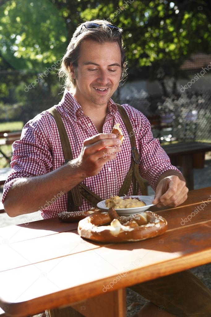 Attractive man eats traditional cheese in a Bavarian beer garden