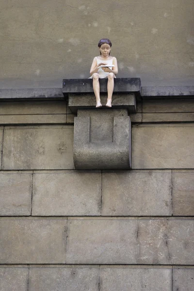 Evi duvarda oturan bir kız figürü — Stok fotoğraf
