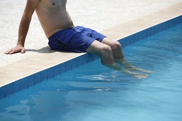 Homem atraente com maiô azul sentado na borda do poo — Fotografia de Stock