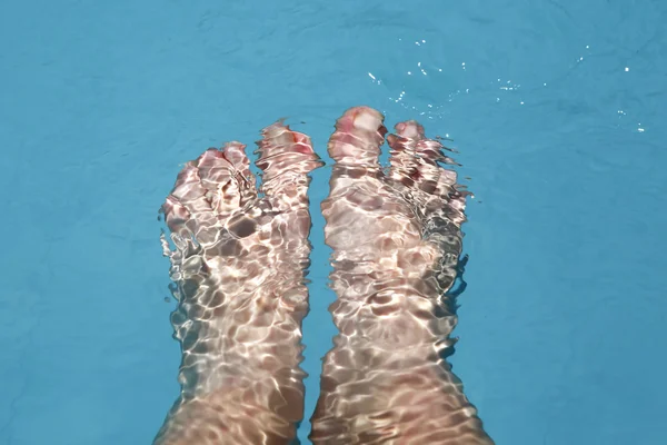 Splashing female feet in a swimming pool — Stock Photo, Image