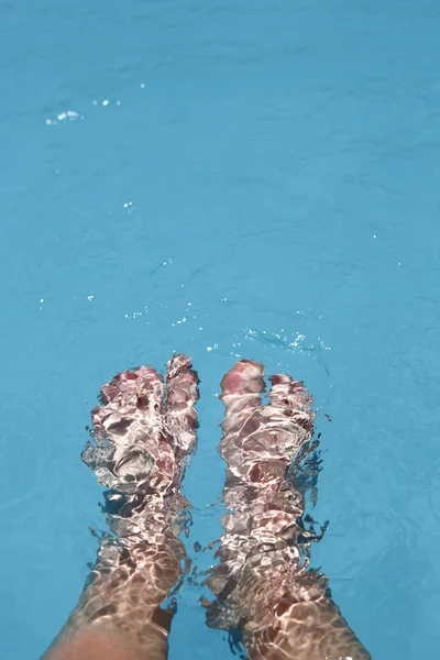 Splashing female feet in a swimming pool — Stock Photo, Image