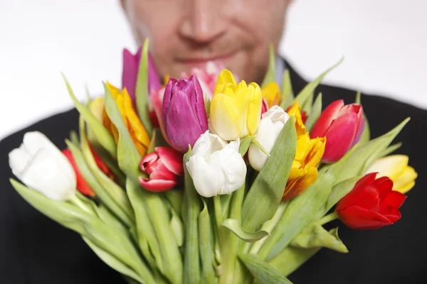 Homem com um lindo buquê colorido de tulipas — Fotografia de Stock