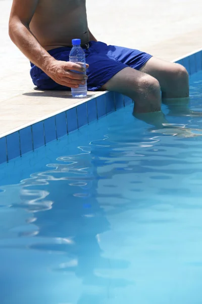 Attraktiver Mann mit blauem Badeanzug und einer Flasche Wasser genießt s — Stockfoto