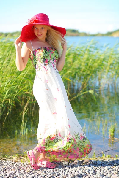 Mooie jonge meisje in een rode hoed en een lichte zomerjurk — Stockfoto