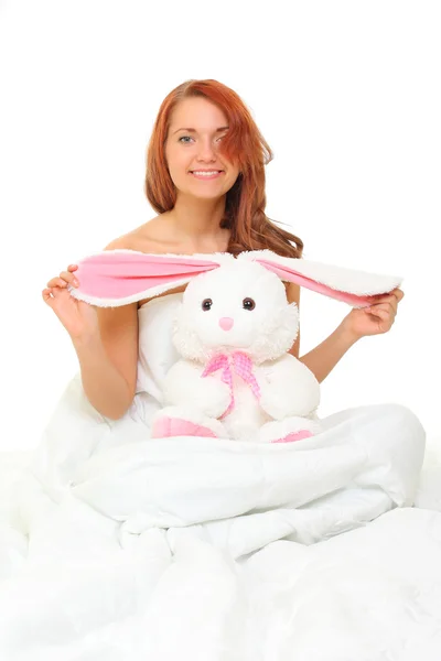 Mladá žena v posteli s plyšový zajíc — Stock fotografie