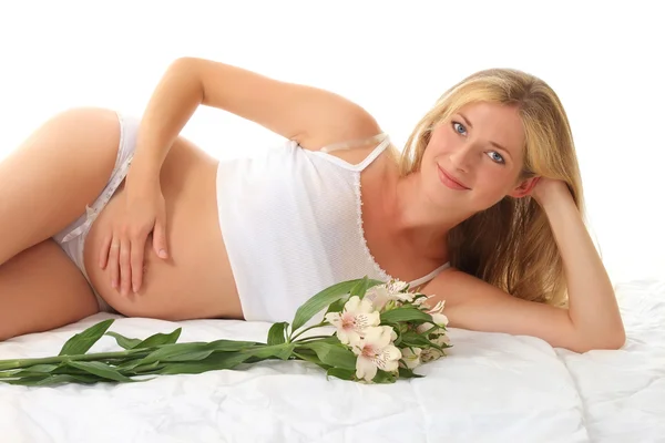 Giovane donna incinta è sdraiata sul fianco e abbraccia la pancia — Foto Stock
