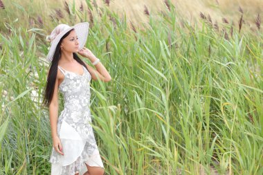 uzun otların bir arka plan üzerinde beyaz elbiseli genç kadın