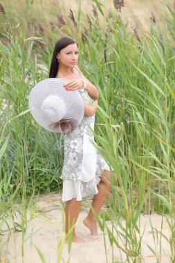 uzun otların bir arka plan üzerinde beyaz elbiseli genç kadın