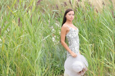 uzun otların bir arka plan üzerinde beyaz elbiseli genç kadın