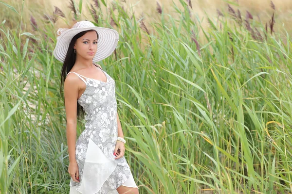 Jonge vrouw in een witte jurk op een achtergrond van hoog gras — Stockfoto