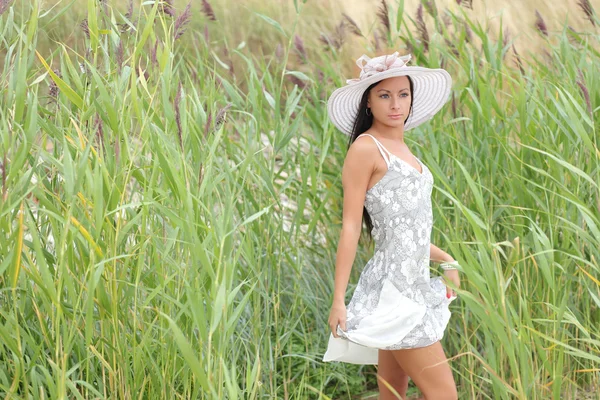 Jovem mulher em um vestido branco em um fundo de grama alta — Fotografia de Stock