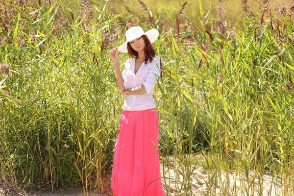 Chica en un sombrero en un paisaje de verano de fondo — Foto de Stock