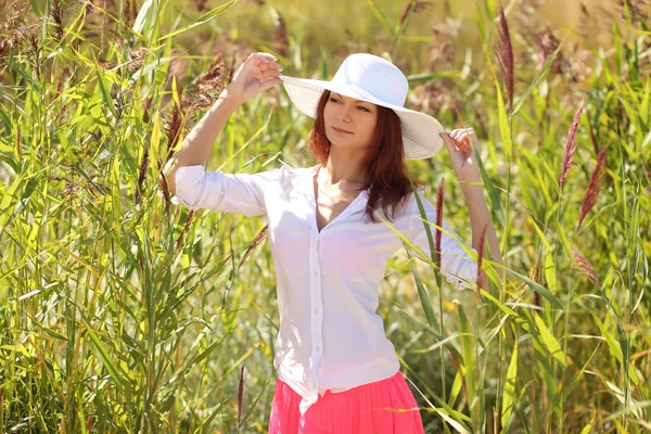Menina em um chapéu em um fundo paisagem de verão — Fotografia de Stock