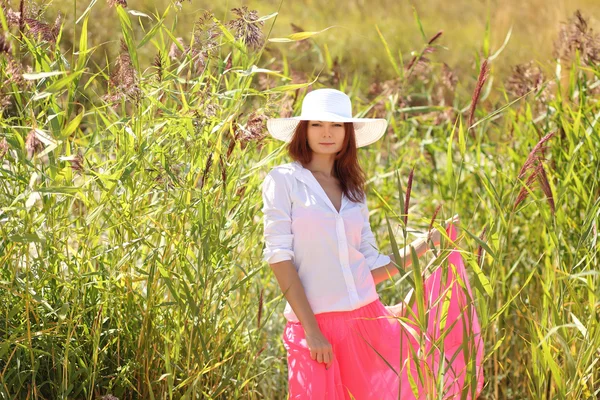 Chica en un sombrero en un paisaje de verano de fondo — Foto de Stock