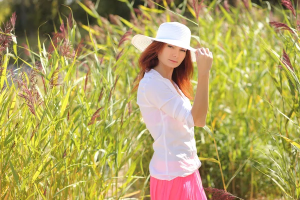 Chica en un sombrero en un paisaje de verano de fondo —  Fotos de Stock