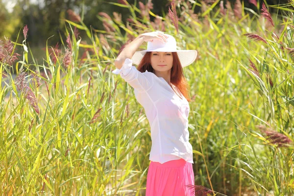 Flicka i en hatt på en bakgrund sommar landskap — Stockfoto