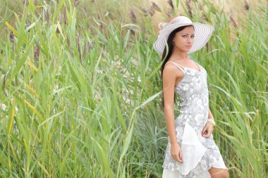 uzun otların bir arka plan üzerinde beyaz elbiseli genç kadın