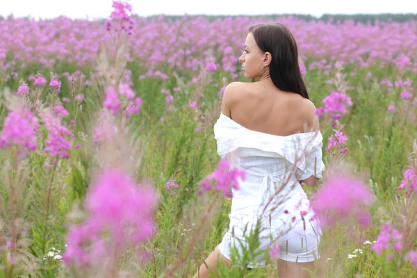 Ung kvinna i en vit klänning på en bakgrund av högt gräs — Stockfoto