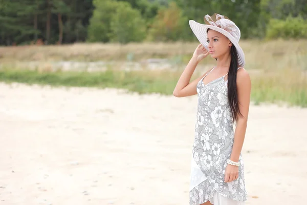 Jonge vrouw in een witte jurk op een achtergrond van hoog gras — Stockfoto