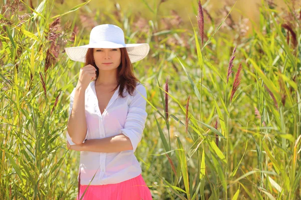 Chica en un sombrero en un paisaje de verano de fondo — Foto de Stock