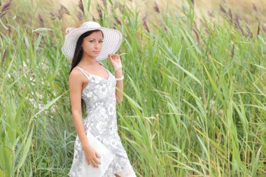 uzun otların bir arka plan üzerinde beyaz elbiseli genç kadın