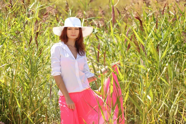Chica en un sombrero en un paisaje de verano de fondo —  Fotos de Stock