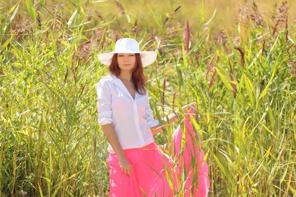 Chica en un sombrero en un paisaje de verano de fondo — Foto de Stock