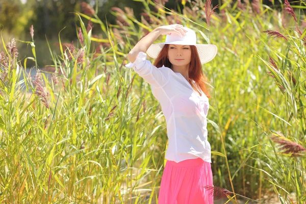 Chica en un sombrero en un paisaje de verano de fondo — Foto de Stock