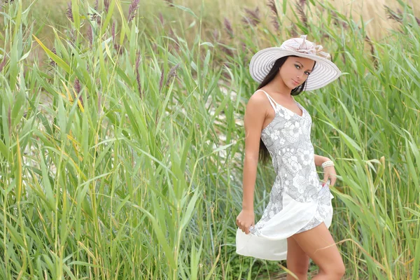 Uzun otların bir arka plan üzerinde beyaz elbiseli genç kadın — Stok fotoğraf