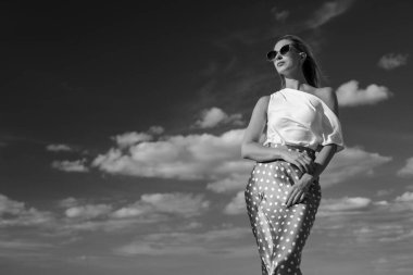 Deniz kenarındaki genç, narin kadın. Kıyafetler içinde poz veriyor.