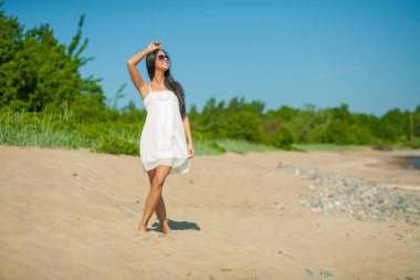 Deniz kenarındaki genç, narin kadın. Kıyafetler içinde poz veriyor.