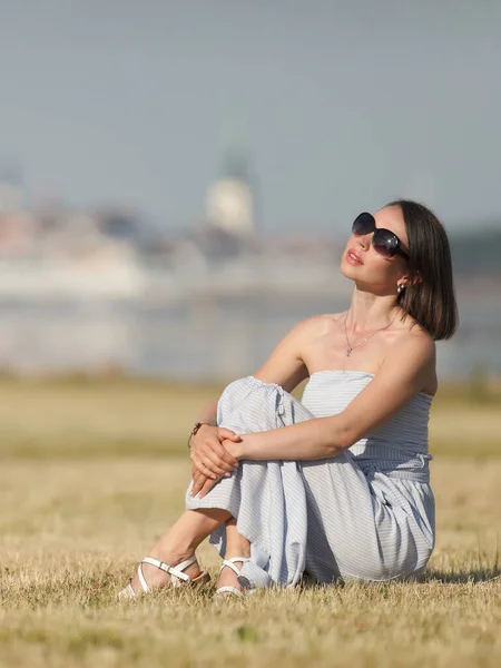 young slender woman by the sea posing in clothes